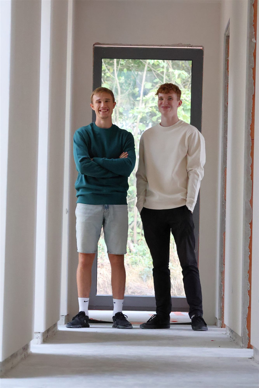 The two founders of ARCHE in a window opening of a house under construction, shot on 21 August 2026